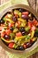 Algerian salad Chlada felfel with green pepper tomato, anchovies and mix of olives close-up in a bowl. vertical top view