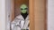Alien with green skin comes into room opening wooden door