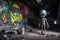 alien with spray can and graffiti piece on wall of abandoned warehouse