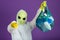 Alien in a white suit holds a bag with plastic bottles and points his finger at the camera, accuses humanity of