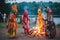 aliens dressed in colorful garments, dancing around bonfire at midsummer festival