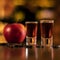 Alkohol shots coffee beans and apple on bar table on blurred background