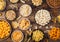 All classic potato snacks with peanuts, popcorn and onion rings and salted pretzels in bowl plates on wooden background. Twirls