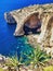 All rocks look like elephants walking in the ocean. Vertical shot with exotic plant at the foreground. Scenic bay surrounded by