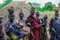 All women with their infants in bright clothes posing to the tourists in the local Mursi tribe village