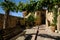 Alley of the city of Assisi with stone facades of historic houses. Arbor with climbing vine plant and flags on the walls