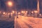 Alley of the evening misty park with burning lanterns, trees and benches.