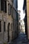 Alley in the historic center of Verona, almost all in the shade, with the facade of the building illuminated at the end of the str