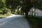 Alley in the park passing next to the building with a colorful flower bed and sitting on a bench in the shade of a large