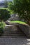 Alley and staircase bordered by flowerbeds and trees