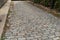 Alley street paved with gray stone blocks set in a running bond pattern bordered by curbs and walls
