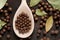 Allspice on a wooden spoon surrounded by a bay leaf and allspice