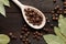 Allspice on a wooden spoon surrounded by a bay leaf and allspice