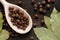 Allspice on a wooden spoon surrounded by a bay leaf and allspice