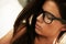 Alluring beauty. Closeup of a lovely young brunette wearing glasses looking downwards - profile.