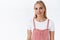 Alluring, sensual and feminine young blond woman with blue eyes in trendy pink overalls, t-shirt, smiling lovely and