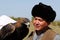 Almaty / Kazakhstan - 09.23.2020 : A man in a fur hat and national dress holds a tamed Golden eagle in his hands