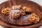 Almond cookies sprinkled with icing sugar on top on a dark brown wooden board on a white background.