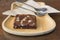 Almond dark chocolate brownie on wood dish.