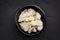 Almond Flakes in Black Bowl over Dark Slate Overhead View.