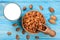 Almond milk in a glass and almonds in a bowl on blue wooden background. Top view