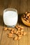 Almond milk in glass with almonds in wooden bowl