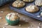 Almond poppyseed muffin in blue wrapping with muffin tin