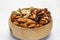 Almonds, cashews and walnuts in a brown wooden bowl on a white wooden background