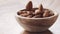 Almonds falling in wood bowl on wooden table in slow motion