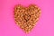 Almonds heap in heart shape on pink background. Valentine\\\'s Day. Flat lay. Raw food.