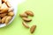 Almonds are not cleaned. A few nuts lie on a white plate on the left side. The plate is not fully visible. Five almonds lie
