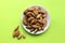 Almonds are not cleaned. Some nuts lie on a white plate in the center. Five walnuts lie separately on a yellow background. View