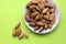 Almonds are not cleaned. Some nuts lie on a white plate in the center. Five walnuts lie separately on a yellow background. View