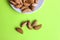Almonds are not cleaned. Some nuts lie on a white plate. The plate is on top and only part is visible. Five almond nuts lie