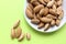 Almonds are not cleaned. Some nuts lie on a white plate on the right side, not fully visible. Five almond nuts lie separately on a