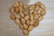 Almonds in the shell in the form of heart on a wooden background, view from the top