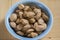 Almonds on table in hard nutshells, group of dry ripened fruits in blue bowl, crop food ingredients ready for cooking