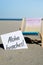 ALOHA BEACHES text on paper greeting card on background of beach chair lounge summer vacation decor. Sandy beach sun