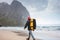 Alone brave tourist with backpack hiking on sea sand among mountains