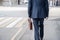 Alone businessman in a blue suit with briefcase in a protective white rubber gloves on the crosswalk on the city street.