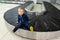 Alone cute caucasian blond toddler boy sitting on empty airport arrival terminal luggage conveyor belt. Lost found child. Travel