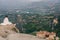 Alone female in the white plaid on the edge of the rock look on the monasteries of Meteora. Female on the rock and monasteries of