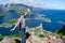 Alone happy woman hiker enjoys the view on cliff edge of lofoten islands, in Norway, Reinebringen