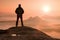 Alone hiker standing on top of a mountain and enjoying sunrise