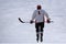 Alone hockey player going to slash puck at outdoor skating rink.