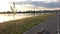 Alone longboard on asphalt road path on river bank in sunset in park out of city with skyline.