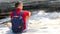 Alone male traveler with a backpack sits near a bubbling mountain river