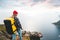 Alone man expeditor wearing professional backpack standing on the edge cliff mountain above sea and looking on epic high landscape