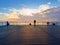 Alone man on pier and look over handrail into water. Sunny sky, smooth water level