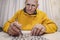 Alone man wearing glasses solving crossword puzzle with pencil in hand